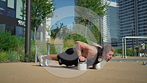 Purposeful caucasian man making push ups and training in urban sport playground