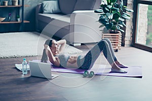 Purposeful strong athletic sportive beautiful attractive sportswoman lying on the floor and doing crunches stretching abs, she is photo