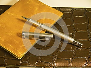Purse, brown notepad and a steel pen