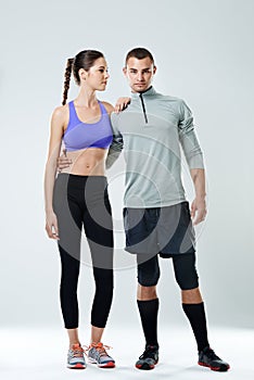 Push each other. Full length shot of a young couple wearing sports clothing against a gray background.