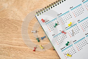 push pins with white yearly calendar on wooden table