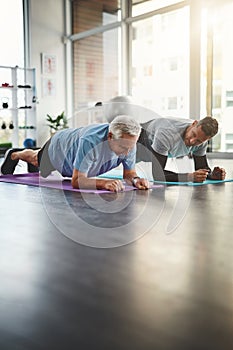 Push up and hold for a few seconds. a young male physiotherapist assisting a senior patient in recovery.