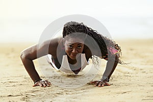 Push-ups fitness african woman doing pushups outside on beach.