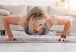 Push-ups at home. Strongly fitness woman doing exercises on mat