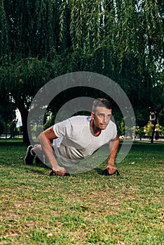 Push ups or press ups exercise by young man while working out on grass crossfit strength training