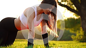 Push ups or press ups exercise by young woman. Girl working out on grass crossfit strength training in the glow of the