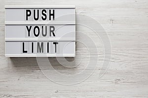 `Push your limit` words on a modern board on a white wooden background, top view. Overhead, from above, flat lay. Space for text