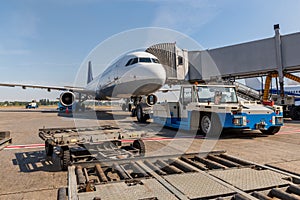 Pushback car is ready to tow a passenger plane, which stands near the telescope gate. Airport life and travel concept