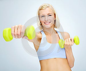 Pushing through the burn towards her best body. Sporty young woman lifting dumbbells while isolated on white.