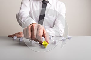 Pushing forward a yellow colored paper boat to advance and stand out from the crowd