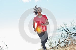 Pushing through the pain. Shot of an attractive young woman running outdoors with her hip injury highlighted.