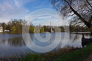Chesma column, reflected in the Large lake of the Catherine Park, surrounded by trees. Against the blue photo