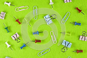 Pushpins paper clips and clips on a green cloth, top view