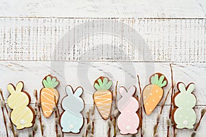 Pussy willows branches and Colorful easter gingerbread rabbit, eggs and chickens on white old wooden background. Festive Easter