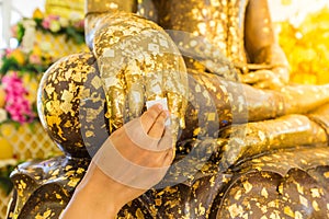 Put gold leaf onto The Buddha statue to gild. photo