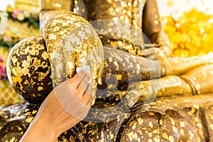 Put gold leaf onto The Buddha statue to gild. photo