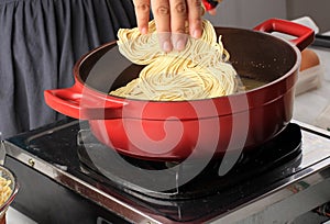 put noodle to boiling water on pan. cooking instant noodle mie telur. Cooking process in the kitchen