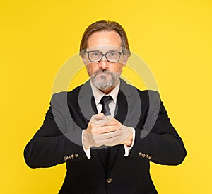 Put two hands into a fist, ready to fight handsome middle aged businessman looking at camera isolated on yellow