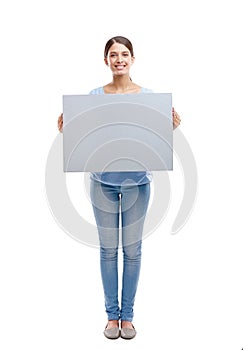 Put your ad right here. Full length studio portrait of an attractive young woman holding up a blank gray sign.