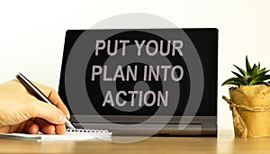 Put your plan into action symbol. Concept words Put your plan into action on the black tablet. Businessman hand with pen. Business