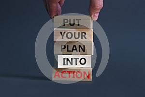 Put your plan into action symbol. Wooden blocks with words Put your plan into action. Businessman hand. Beautiful grey background