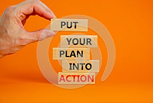 Put your plan into action symbol. Wooden blocks with words Put your plan into action. Businessman hand. Beautiful orange