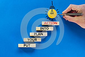 Put your plan into action symbol. Wooden blocks with words Put your plan into action. Light bulb icon. Businessman hand, pen. Blue