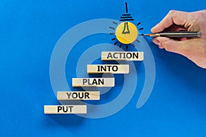 Put your plan into action symbol. Wooden blocks with words Put your plan into action. Light bulb icon. Businessman hand, pen. Blue