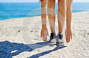 Put on your shoes and do it. a young woman stretching while out on the beach on a sunny day.