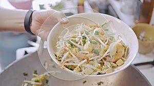 Puting Pad Thai from the pan into dish ready to eat