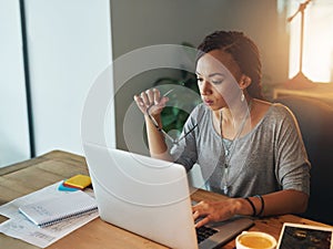 She puts a lot of thought into her work. Cropped shot of a young woman using her laptop while working late in her office