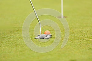 Putter golf club hammering a golf ball into a hole