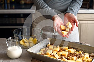 Putting cheese in the baking tray with potato slices and bacon