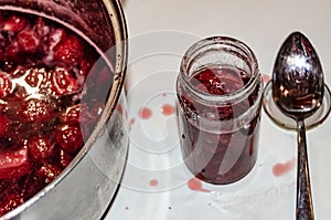 Putting cooked strawberyes in the glass jars - shugar adiction photo