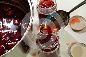 Putting cooked strawberyes in the glass jars - shugar adiction