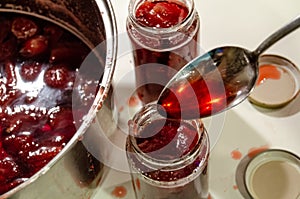 Putting cooked strawberyes in the glass jars - shugar adiction photo
