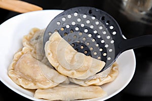 Putting delicious dumplings (varenyky) on plate
