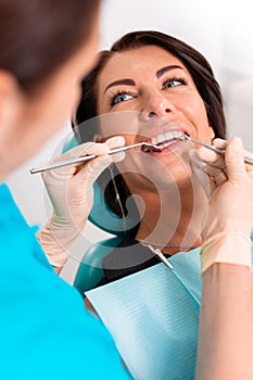 Putting dental braces to the woman`s teeth at the dental office. Dentist examine female patient with braces in dental