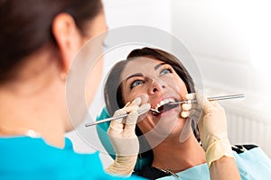 Putting dental braces to the woman`s teeth at the dental office. Dentist examine female patient with braces in dental