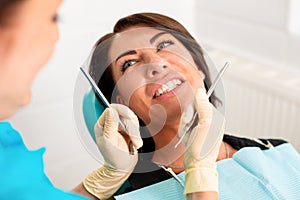 Putting dental braces to the woman`s teeth at the dental office. Dentist examine female patient with braces in dental