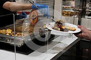 Putting food on tourist plate. Serving dinner at restaurant in an all-inclusive resort in Turkey. Healthy safety measures during