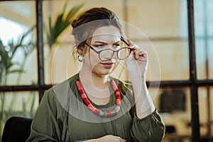Young prosperous businesswoman putting her glasses on photo