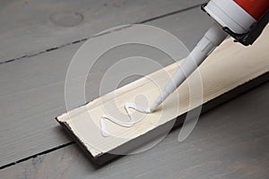 Putting glue on a piece of wooden baseboard