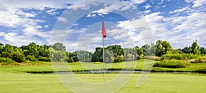 Putting green with a flag at a golf course on a summer day