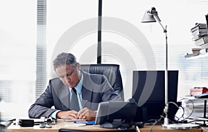 Putting the hard yards in. A senior businessman working hard at his desk.