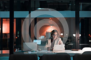 Putting her career first. a businesswoman using a laptop at her desk during a late night at work.