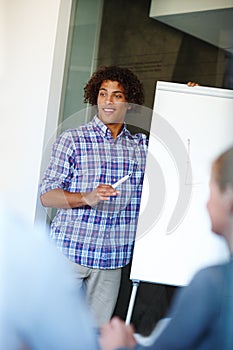 Putting his corporate strategy forward. Casual young businessman giving a presentation using a whiteboard.