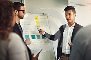 Putting his plan into action. a young man giving a presentation to colleagues in an office.