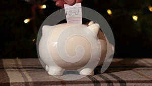 Putting IOU into piggy bank savings in Christmas tree background