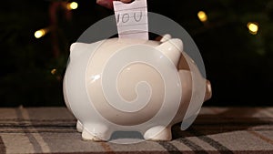 Putting IOU into piggy bank savings in Christmas tree background